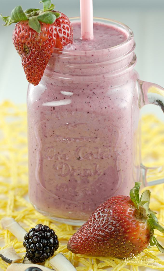 Triple Berry Coconut Smoothie in a glass with a straw.