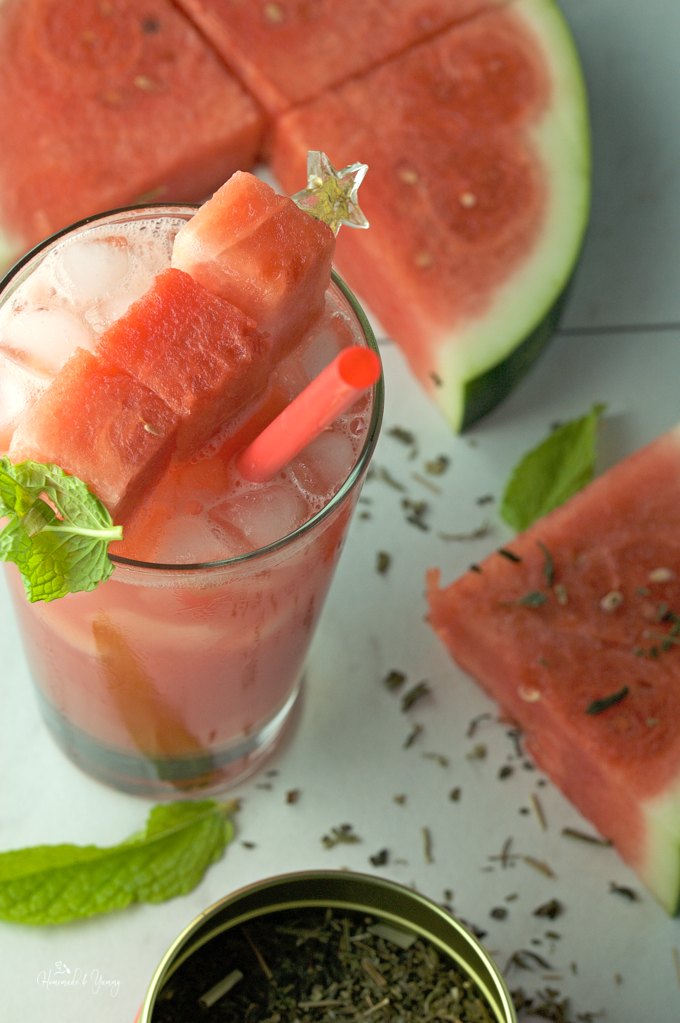 Slices of watermelon, a container of tea leaves and a glass of juice.