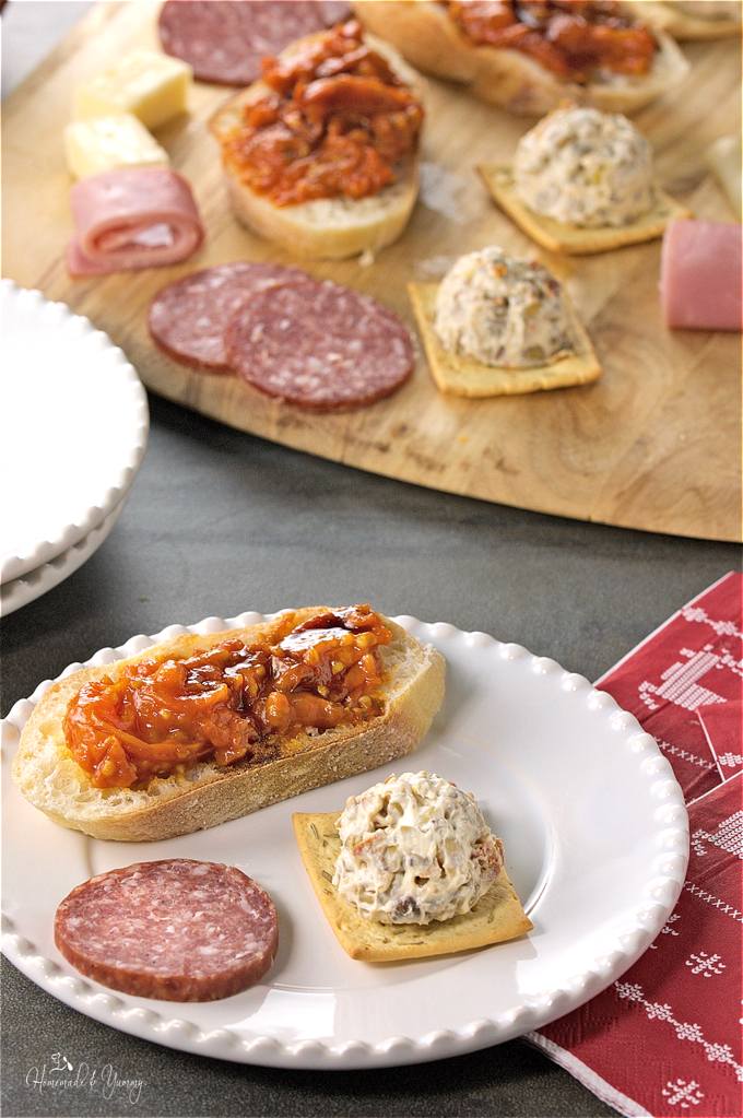 A assortment of appetizers on a wooden board, with cream cheese balls in the mix.