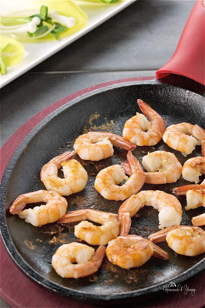 Shrimps cooking in a cast iron skillet.