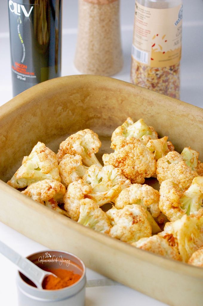 Cauliflower florets in a baking dish dusted with smoked paprika ready to roast.