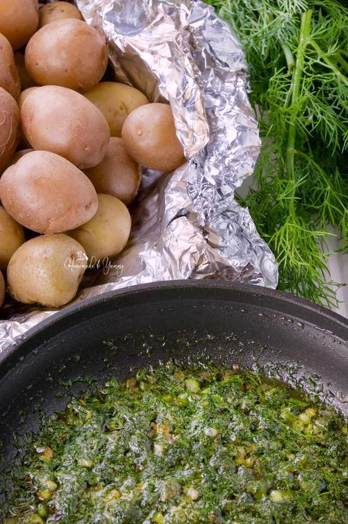 Baby potatoes in a foil packet, dill and onions cooking in a frying pan.