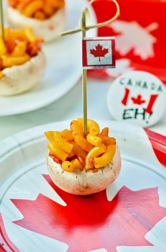 A close up of 1 single mushroom bite on a plate with a Canadian flag.