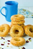 A pile of Oatmeal Breakfast donuts piled on the table with a blue coffee mug in the background.