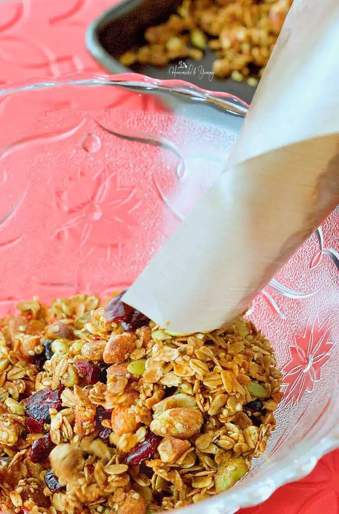 Pouring the holiday granola into a large glass bowl.