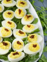 A beautiful platter of flavoured devilled eggs with garnished with arugula on a table.