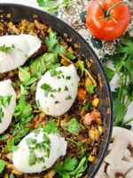 Poached Eggs & Lentil Hash in a pan sprinkled with fresh parley, ready to serve.