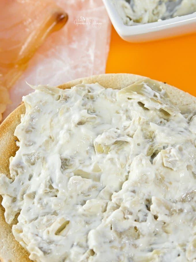 Artichoke cream cheese slathered on top of a toasted bagel.