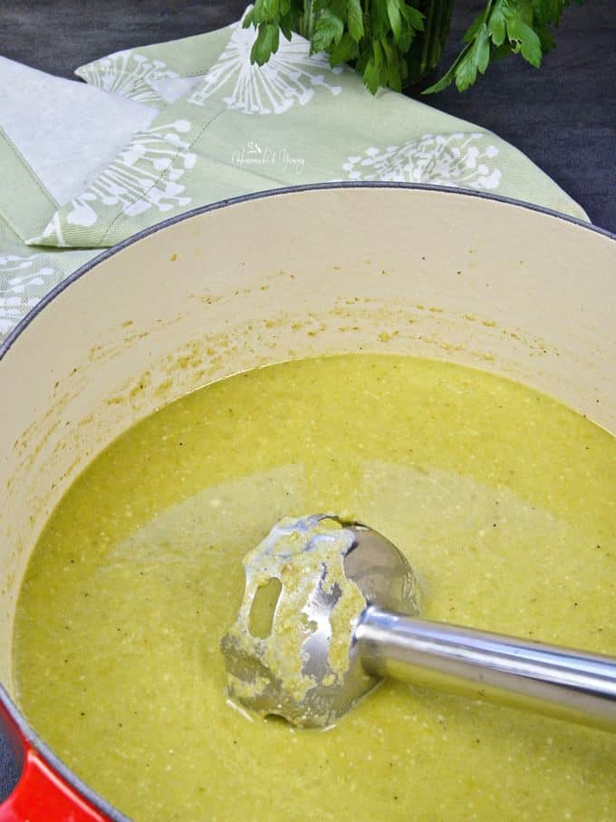 Asparagus soup getting blended with an immersion blender.