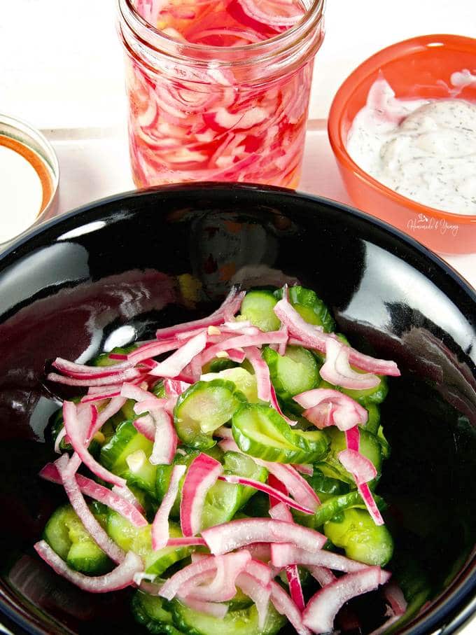 Close up of cucumbers and pickled onions in a bowl ready for the salad dressing.