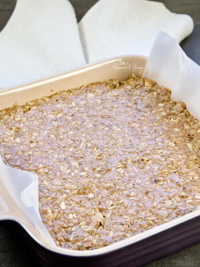 Granola bar mixture in a square dish, ready for the fridge.