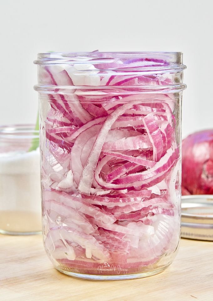 A glass jar of sliced red onions before the pickling vinegar is added.