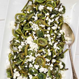 Roasted Fiddlehead Ferns on a serving platter garnished with feta cheese.