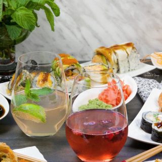 Wine Spritzers on a table with plates of sushi.