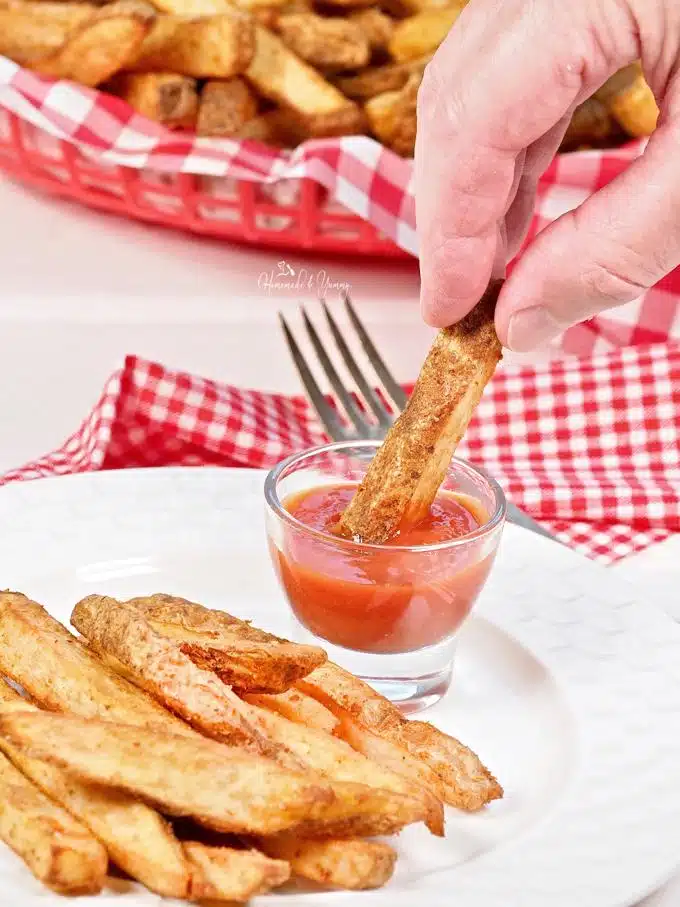 Crispy fry getting dunked into ketchup.