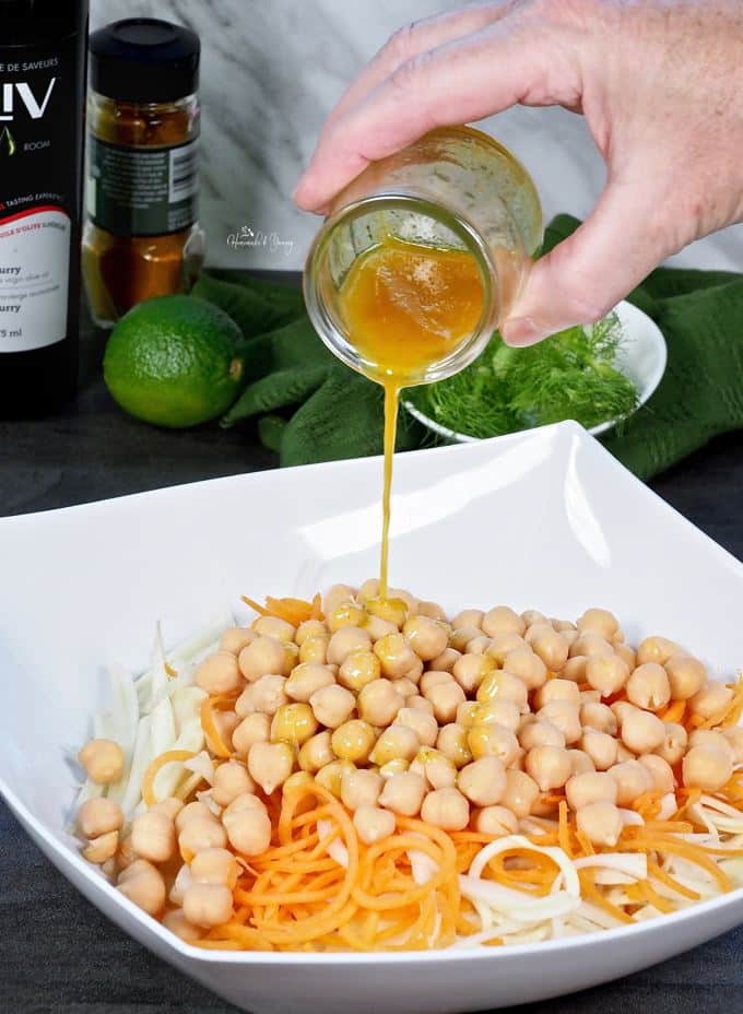 Curry vinaigrette getting poured over the chickpeas, carrots and fennel.