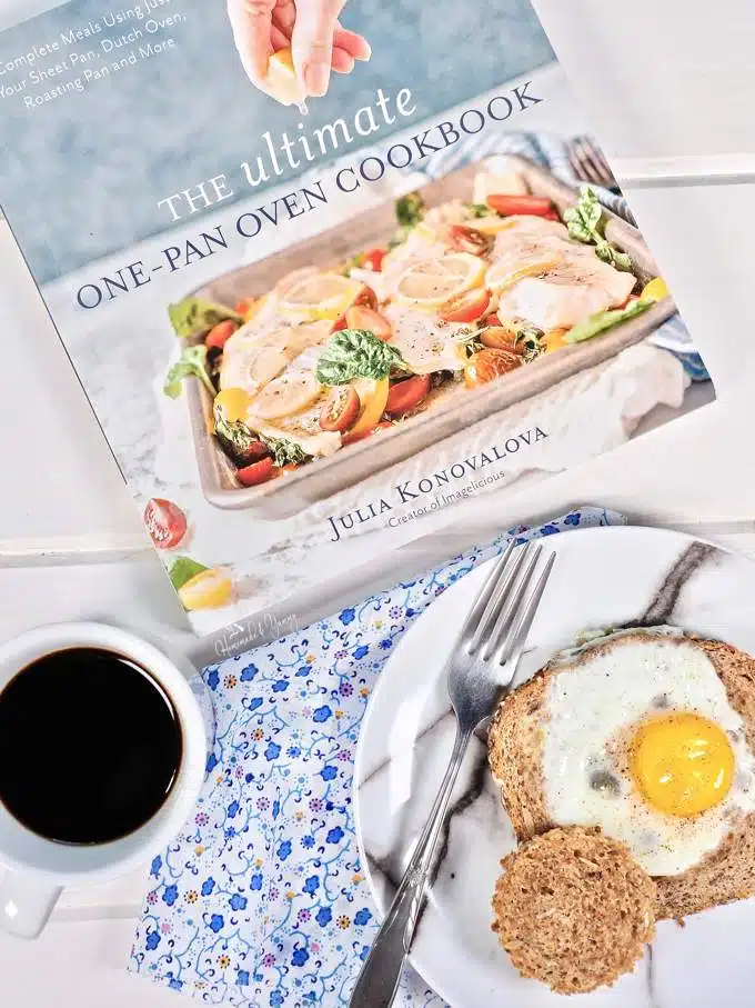 Overhead shot of the cookbook (for giveaway) and a Smoked Salmon Egg In A Hole on a plate with a cup of coffee.