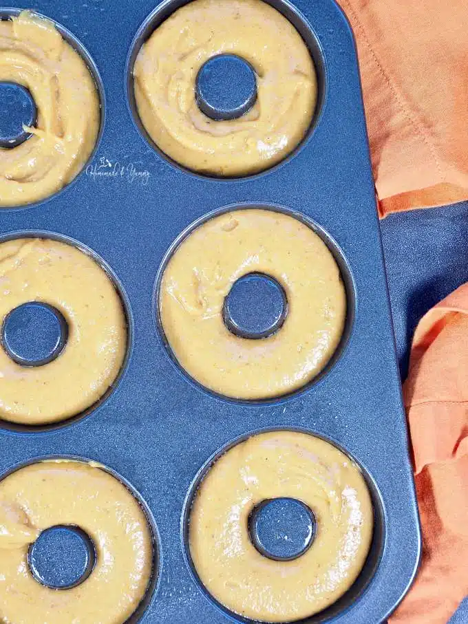 Donut batter piped into a donut pan.