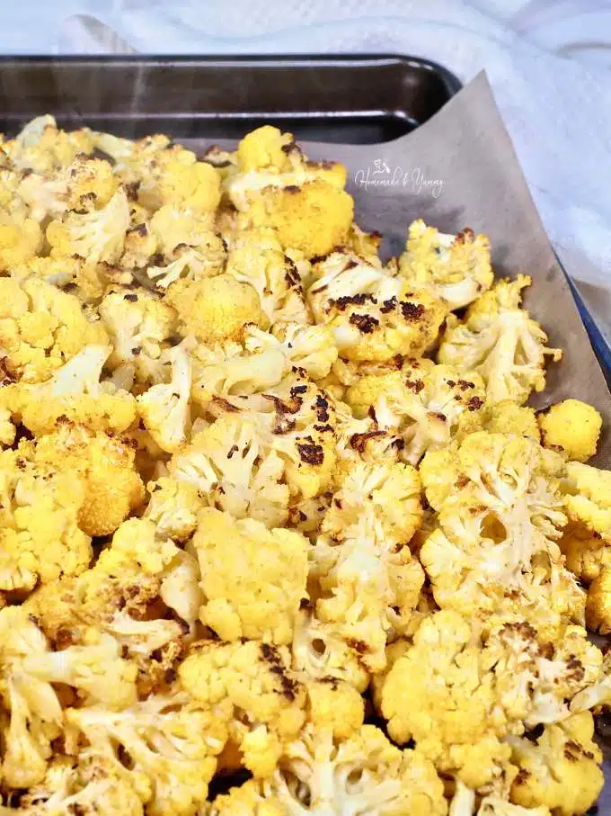 A sheet pan of orange cauliflower pieces right out of the oven