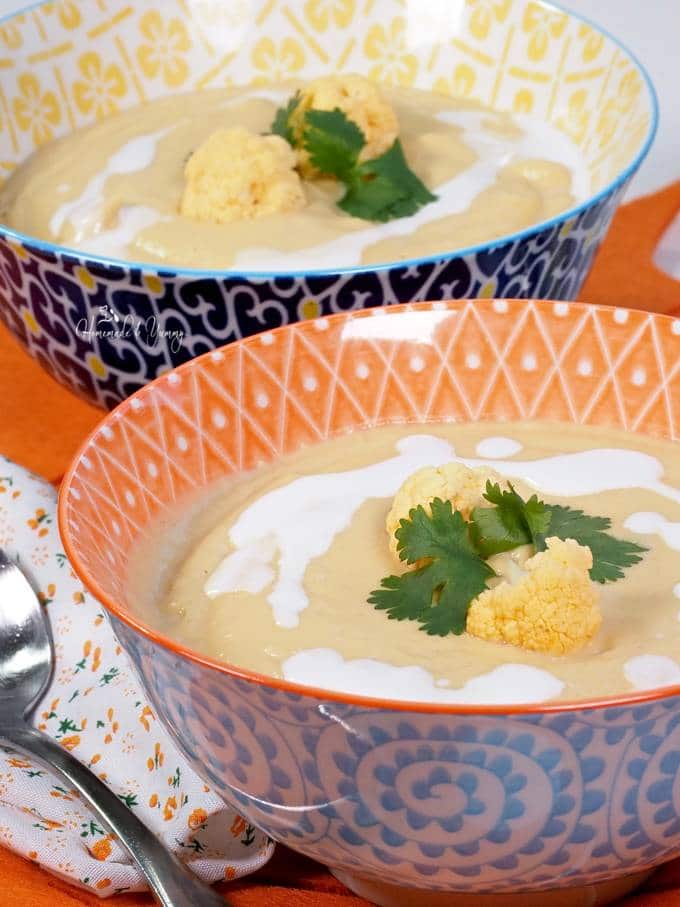 Roasted Orange Cauliflower soup in a bowl garnished with coconut milk
