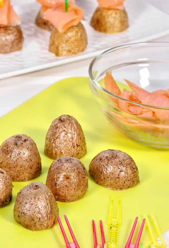 Potato appetizers getting topped with smoked salmon.
