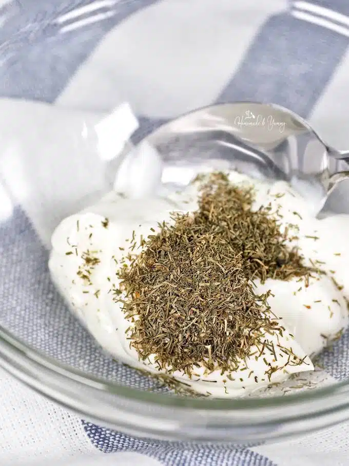 Sour cream and dill in a bowl ready to be mixed into salad dressing.