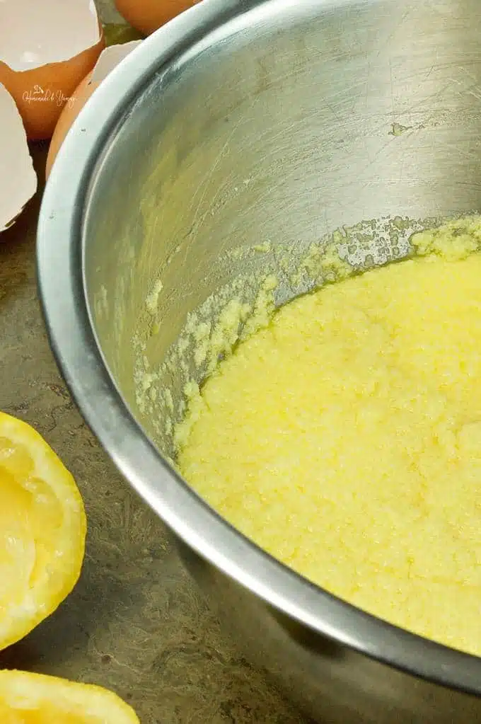 Lemon juice, eggs, sugar and eggs getting mixed in a bowl.