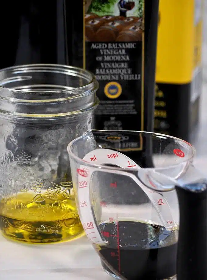 Olive oil in a jar, balsamic vinegar in a measuring cup.