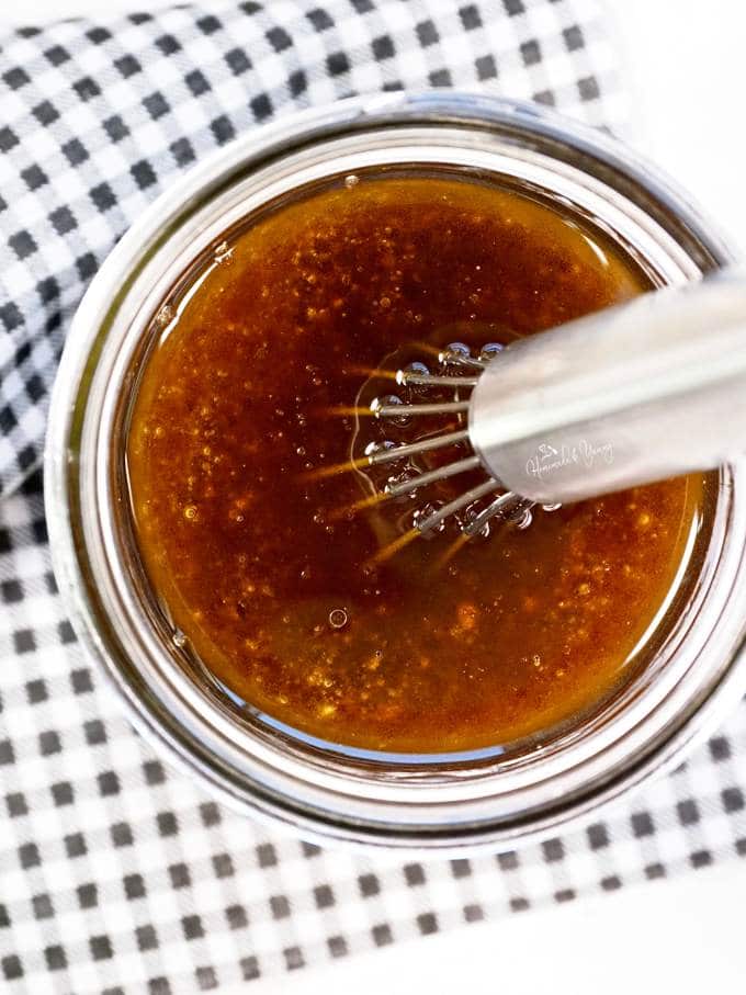 Overhead shop of the meat marinade in a jar with a whisk.