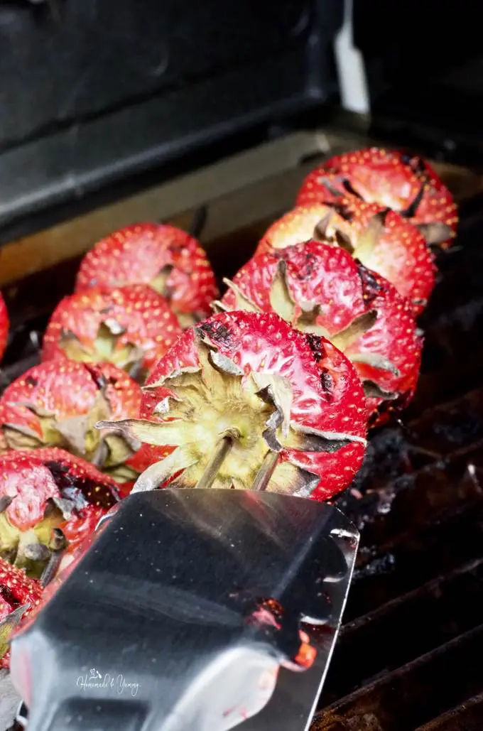 Strawberry skewers getting cooked on the grill.