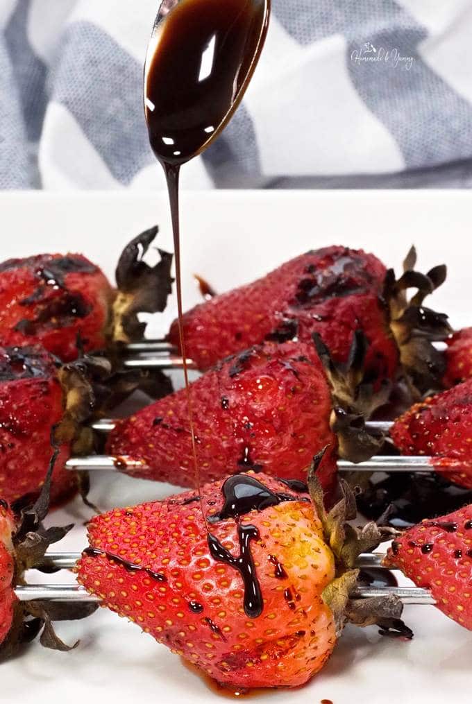 Grilled strawberries getting drizzled with balsamic glaze.