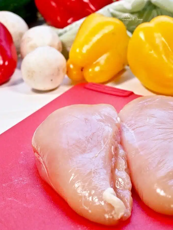 Raw boneless, skinless chicken breasts on a cutting board