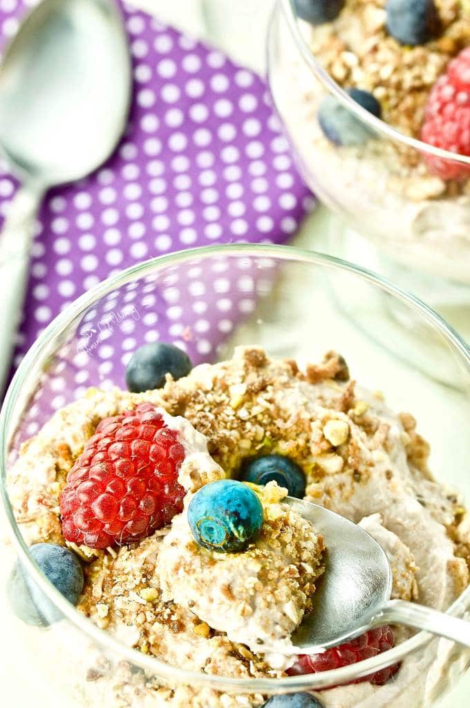 A spoon in a bowl of yogurt, berries and granola.