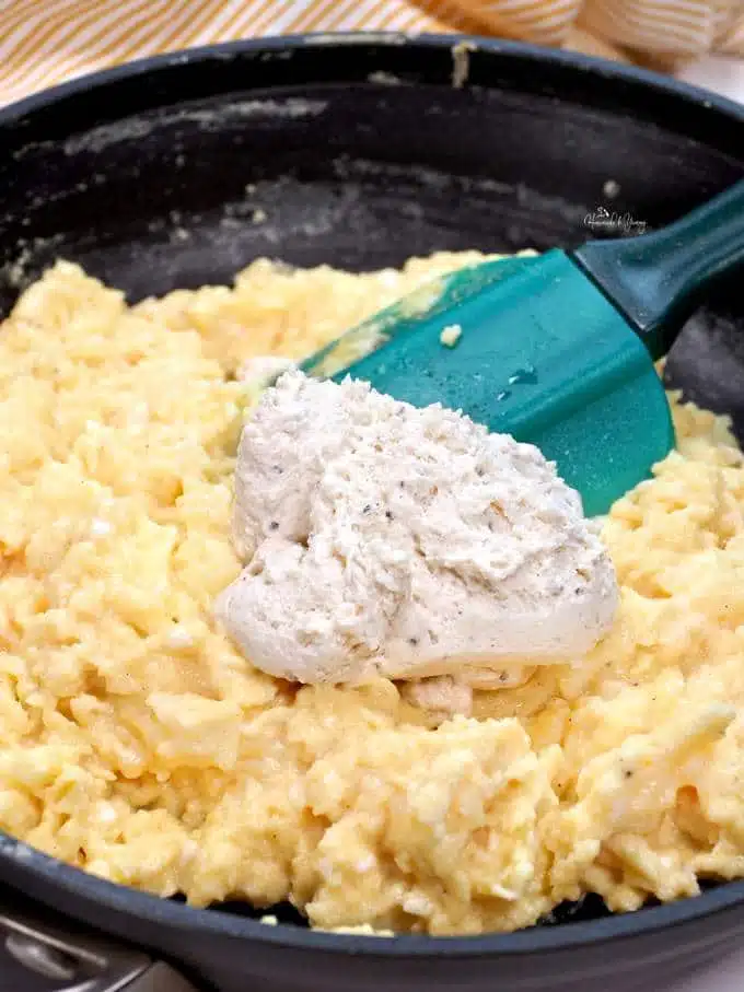 Close up of scrambled eggs in a pan with cream cheese.