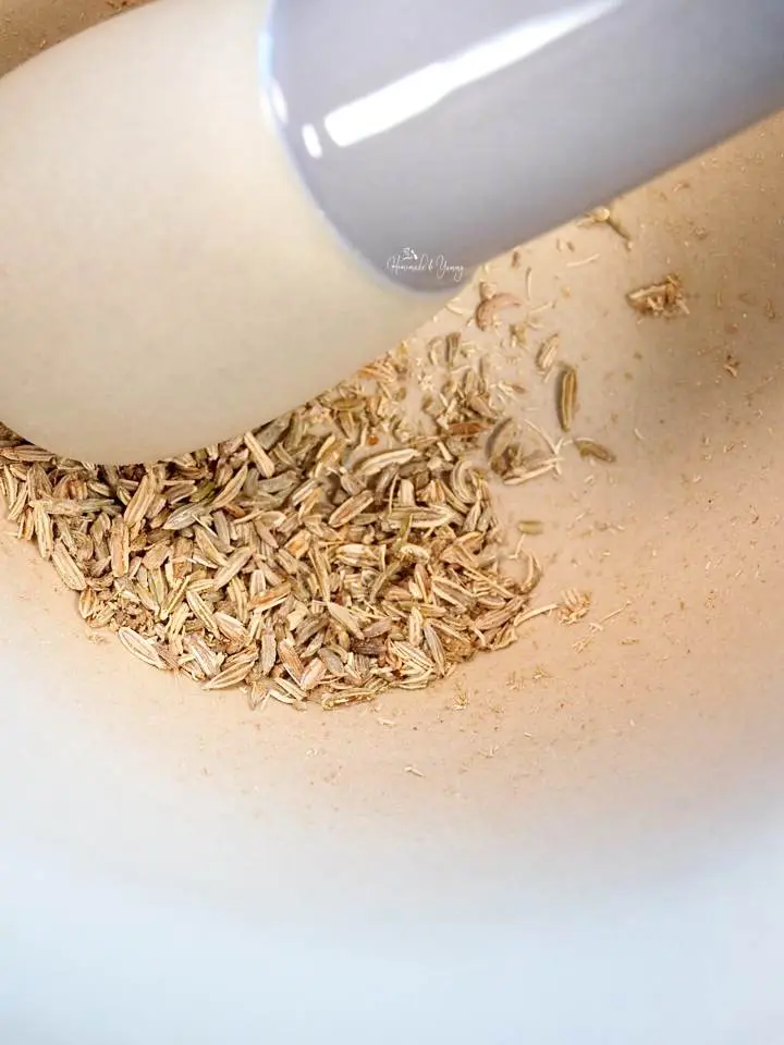 Fennel seeds getting crushed in a mortar and pestle.