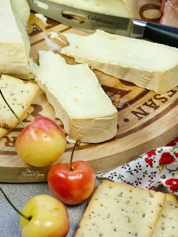 Slices of smoked brie cheese on a wooden board.