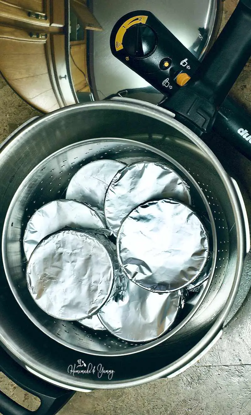 Foil wrapped ramekins of pudding in a pressure cooker