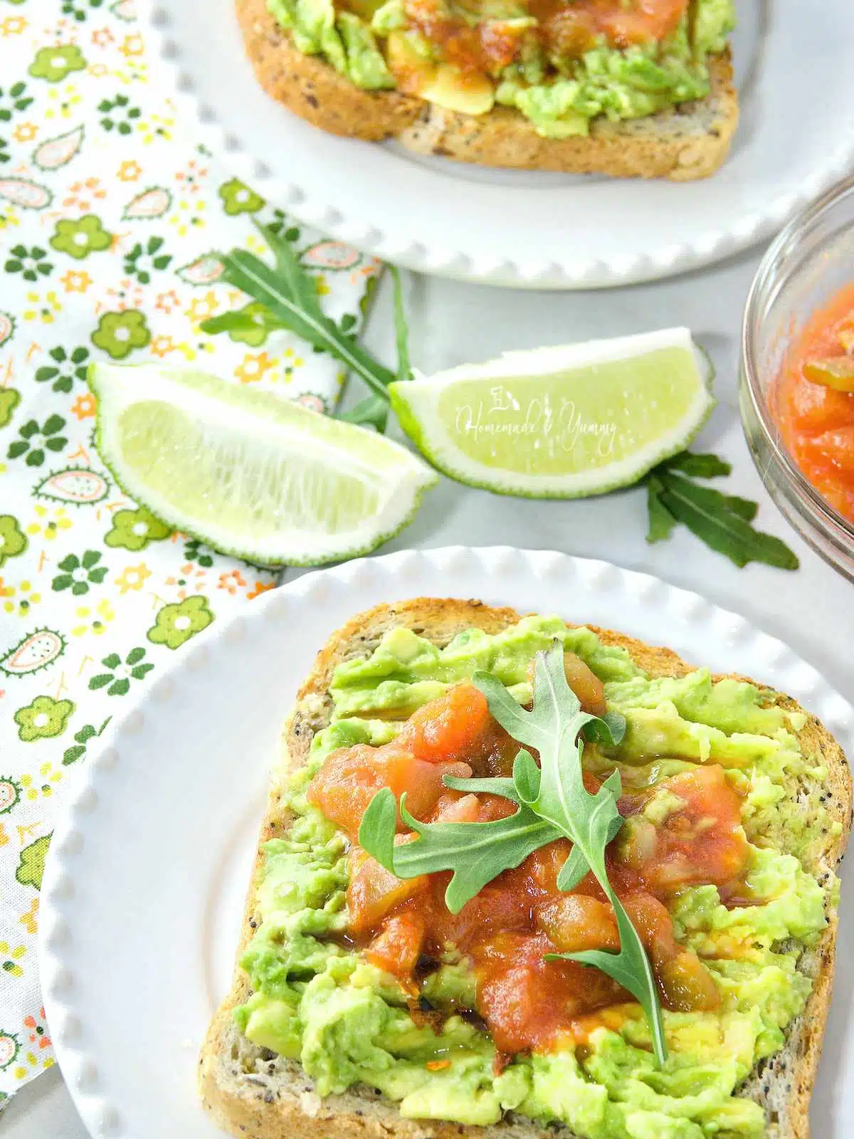 Mashed avocado on toast, topped with salsa and arugula.