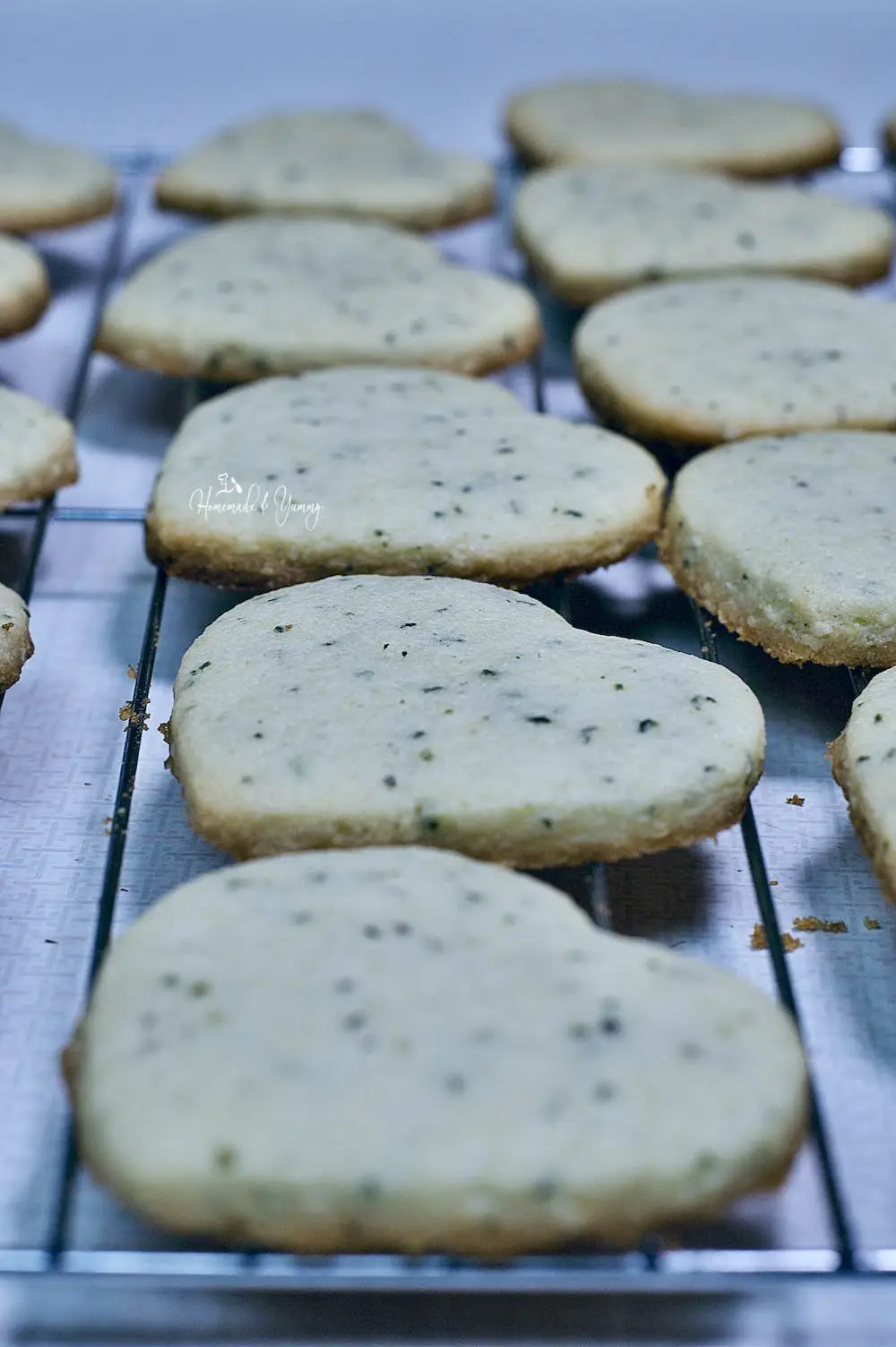 Fresh baked heart shaped cookies with hemp seeds cooling on a rack