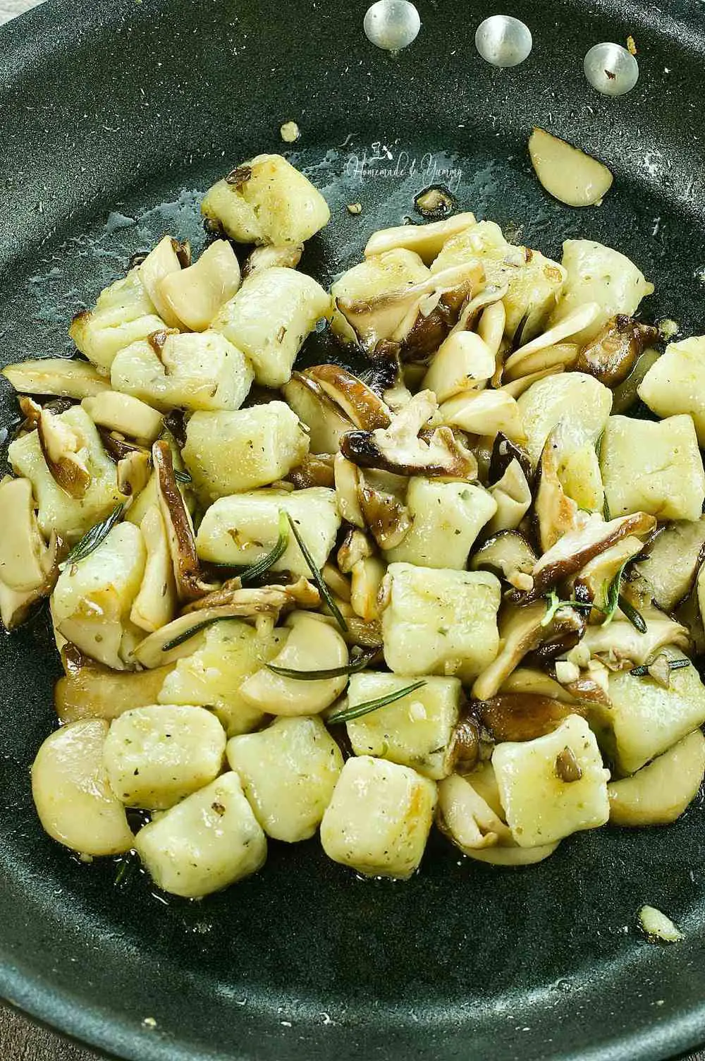 Combining the cooked mushrooms and cooked gnocchi together in a frying pan.