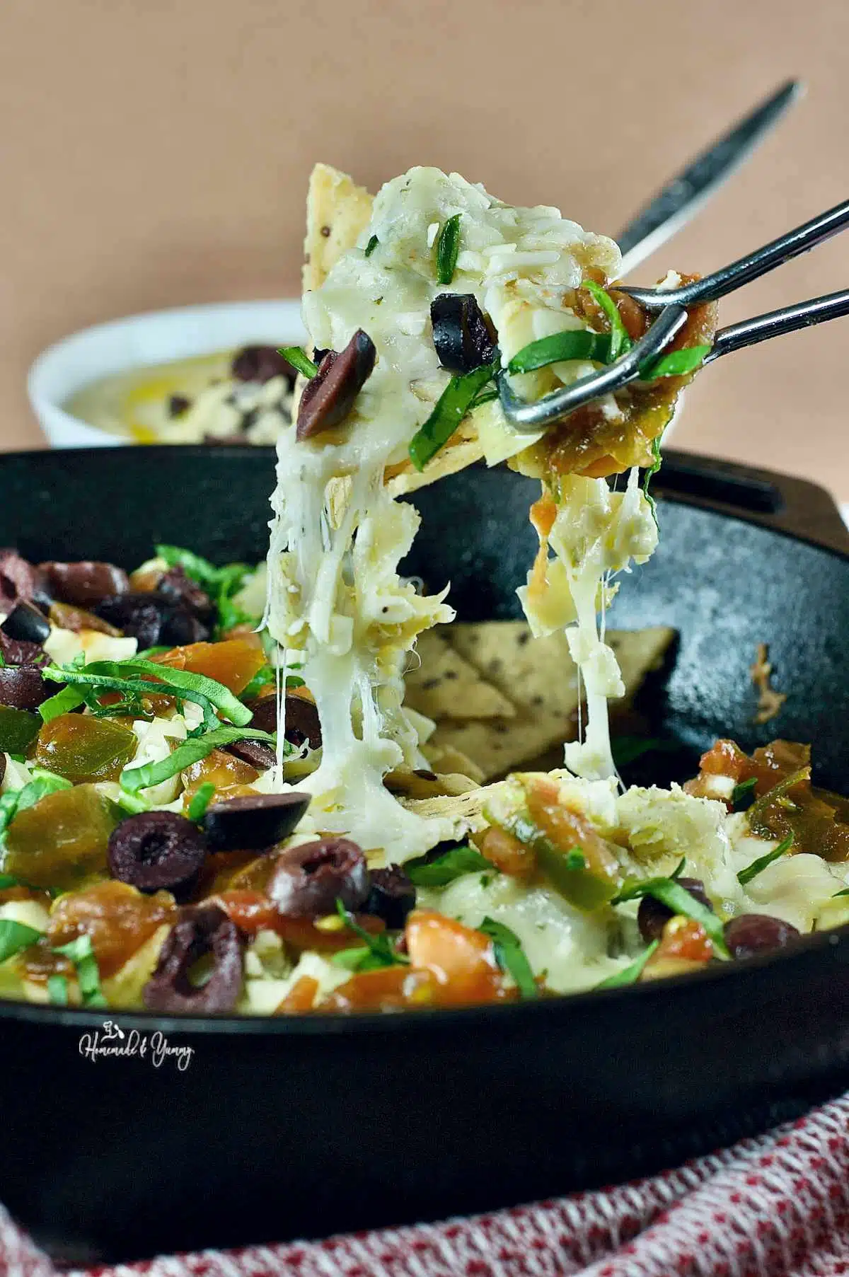 A pan Greek nachos, with a bowl of hummus in the background.