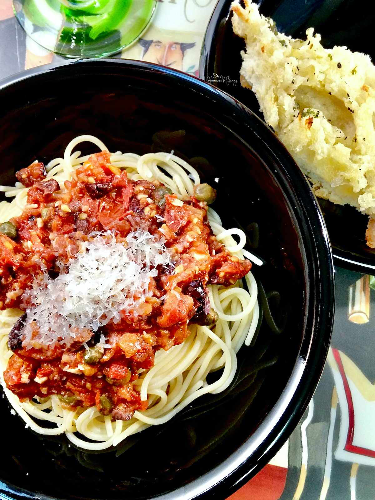 Fresh Tomato Puttanesca sauce on pasta in a black bowl.