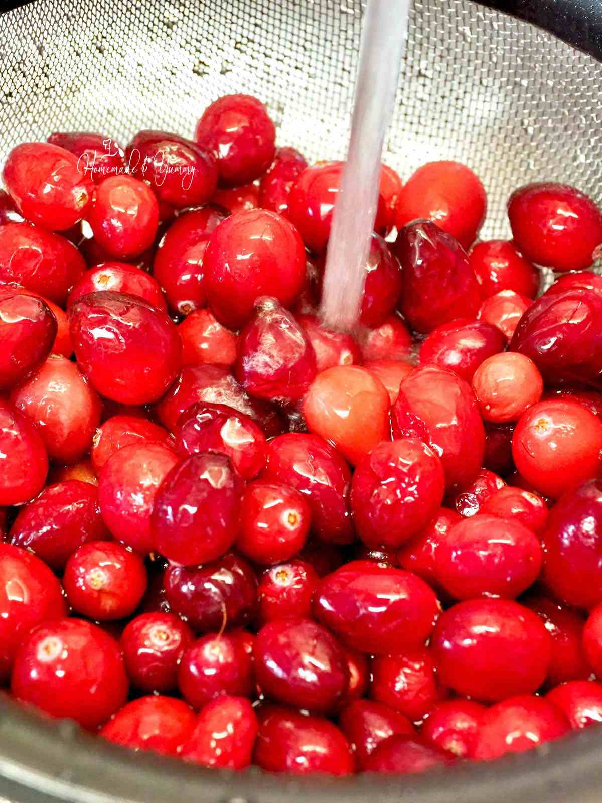 Rinsing fresh cranberries in a strainer.