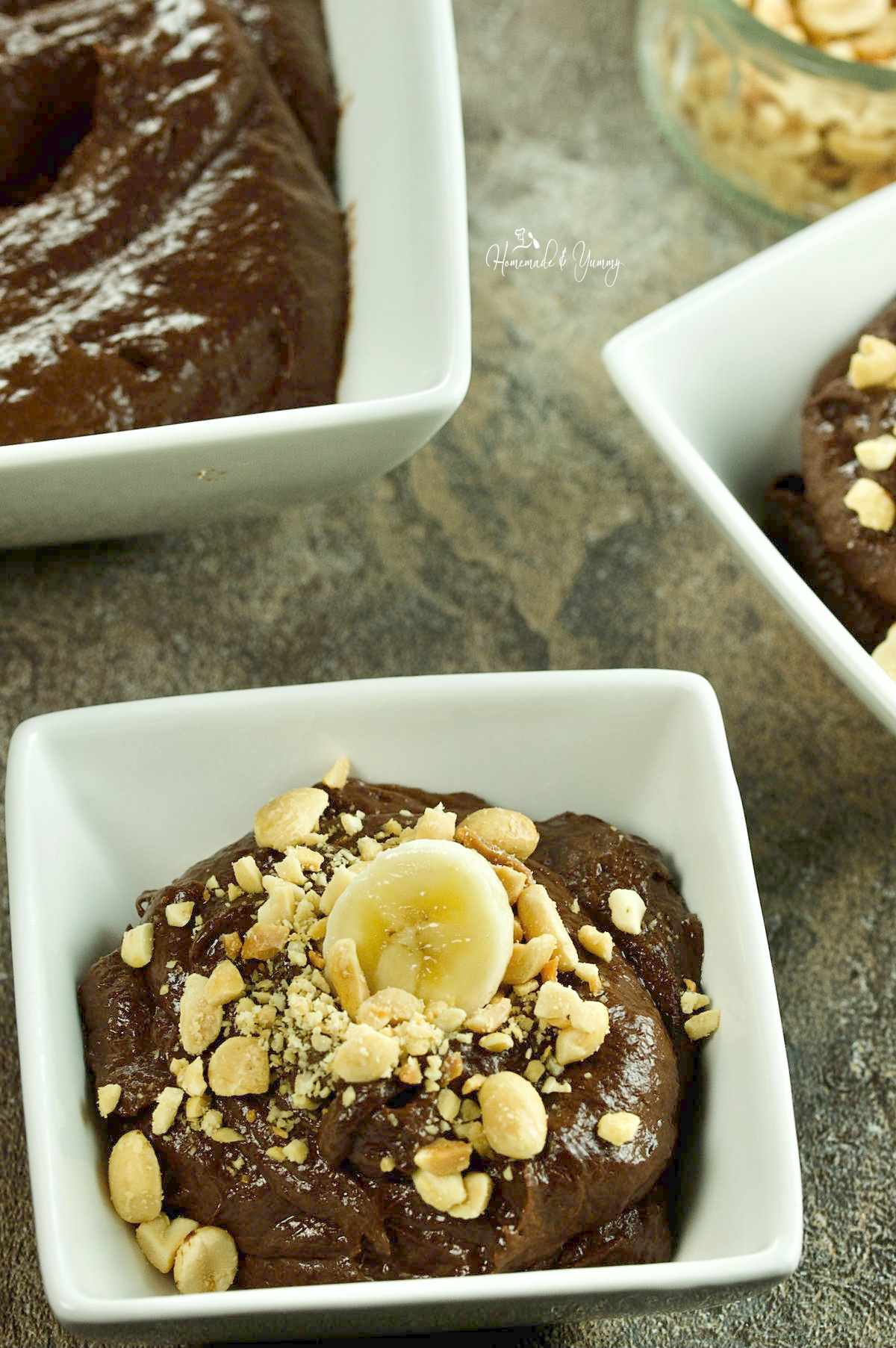Healthy Chocolate Banana Pudding in a bowl garnished with peanuts and banana slices.