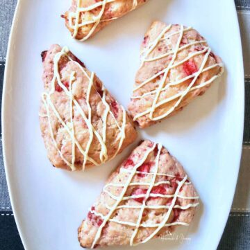4 strawberry scones on a white serving plate.