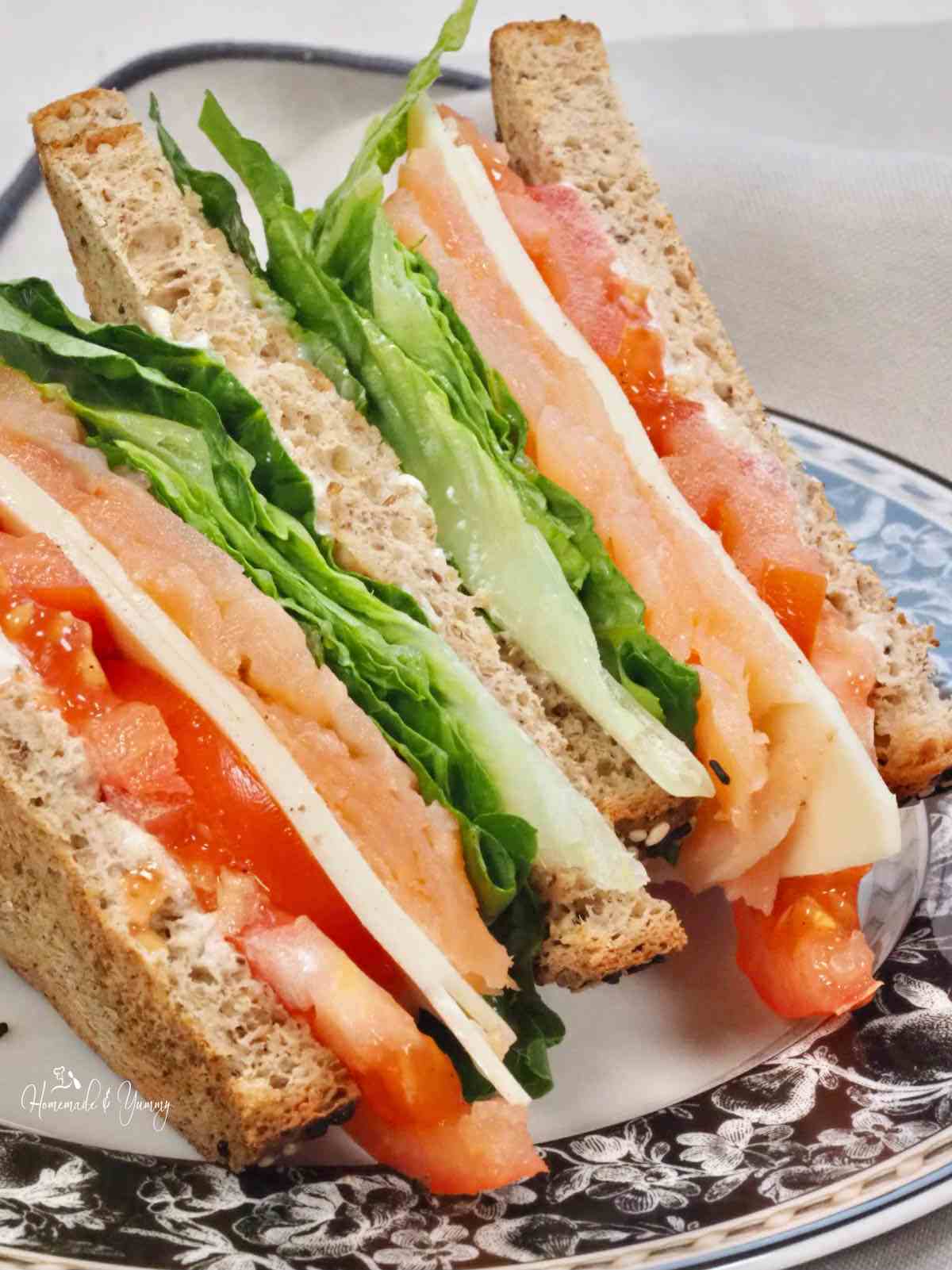 Sandwich with tomatoes, cheese, lettuce and smoked salmon.
