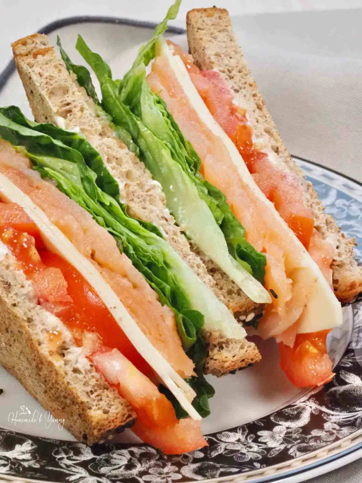 Sandwich with tomatoes, cheese, lettuce and smoked salmon.
