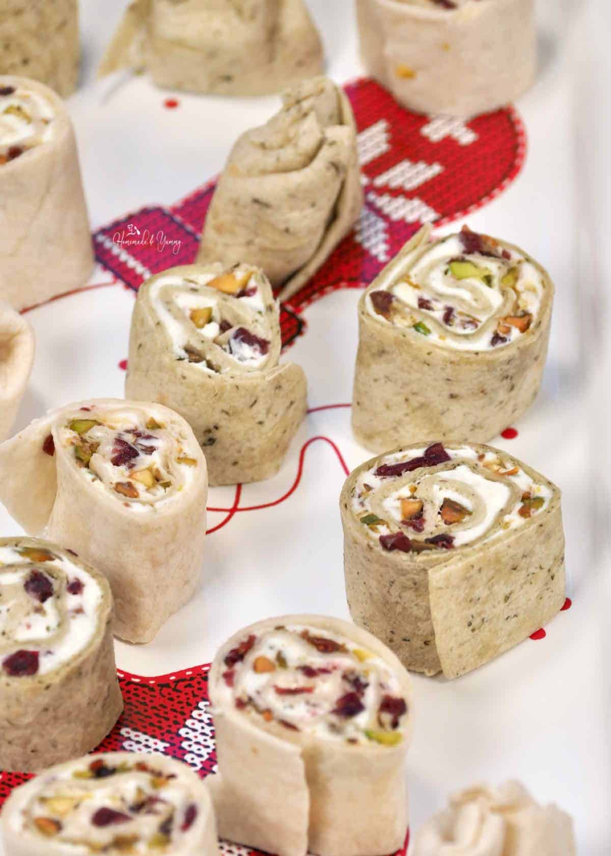 A tray of festive pinwheel appetizers with cream cheese, cranberries and nuts.