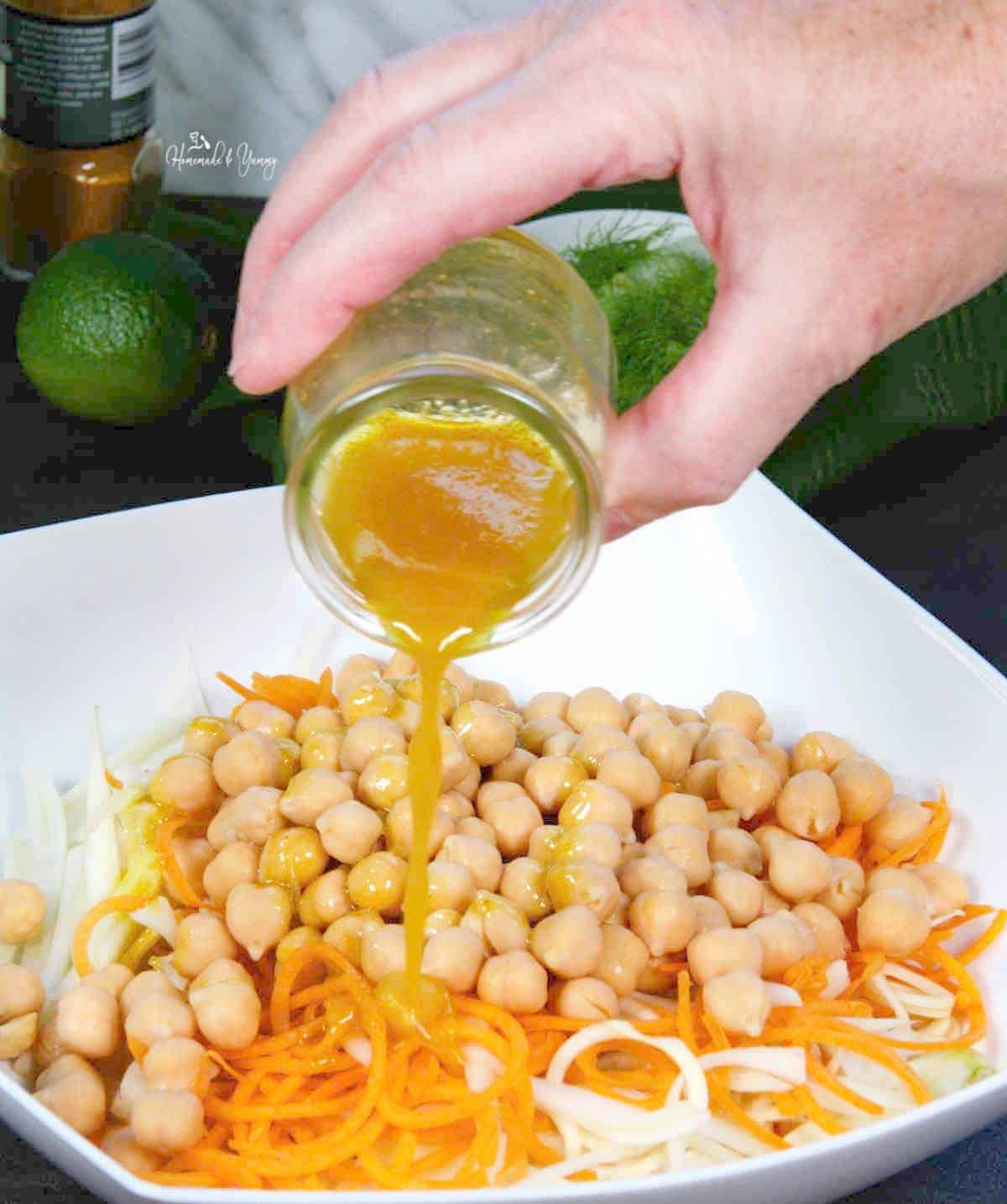 Pouring salad dressing over the salad ingredients.
