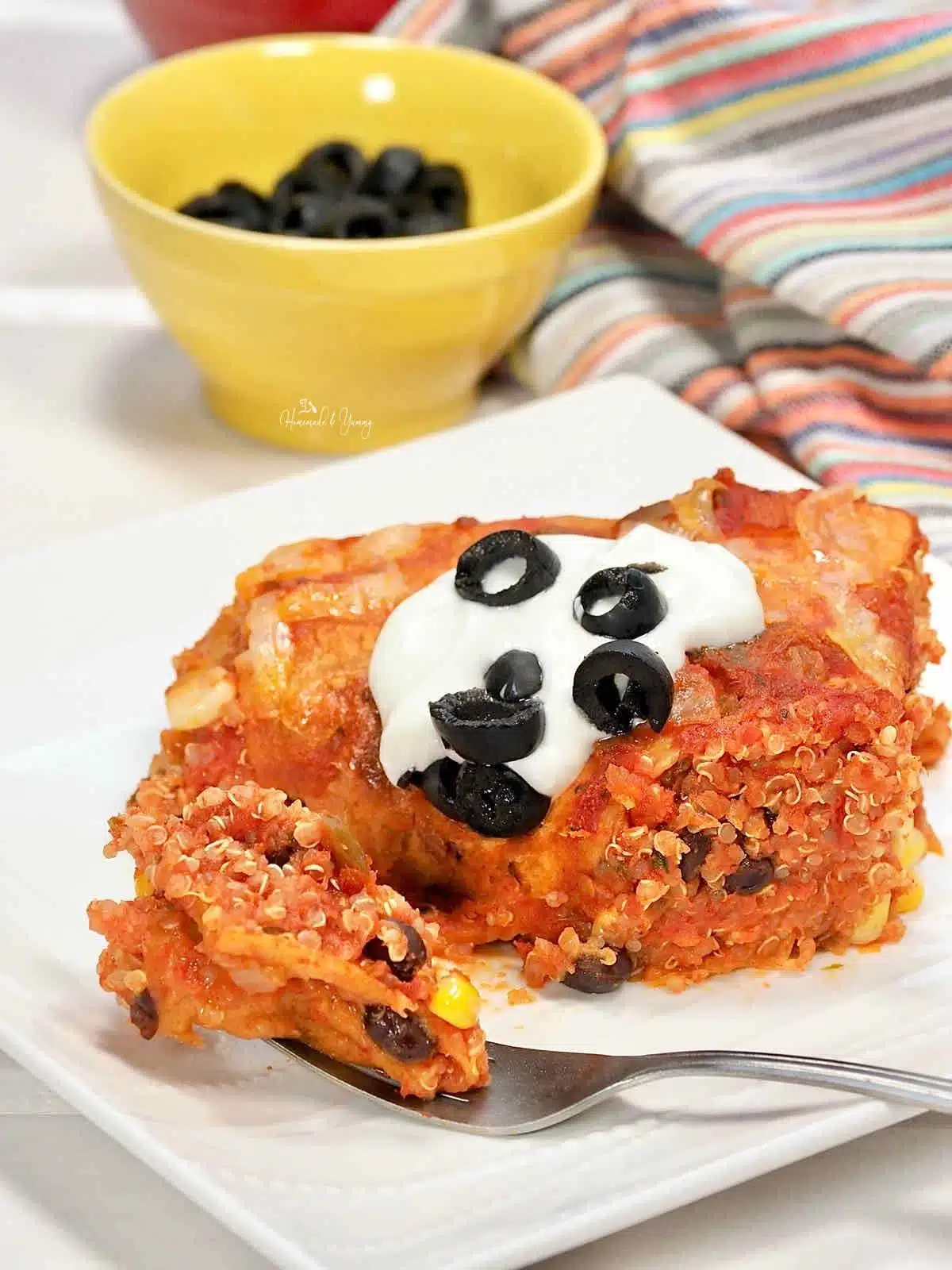 Quinoa Mexican lasagna topped with sour cream and olives.